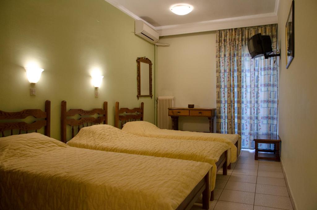 a hotel room with three beds and a window at Hotel Costis in Ptolemaida