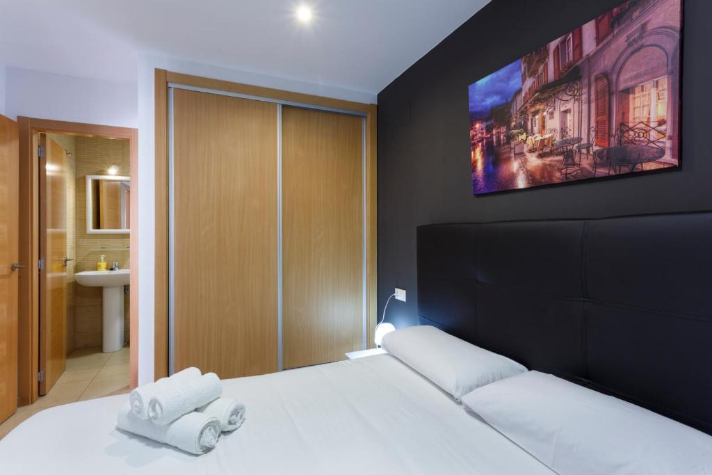 - une chambre avec un lit blanc et une télévision murale dans l'établissement Apartamentos Santa Barbara, à Alicante