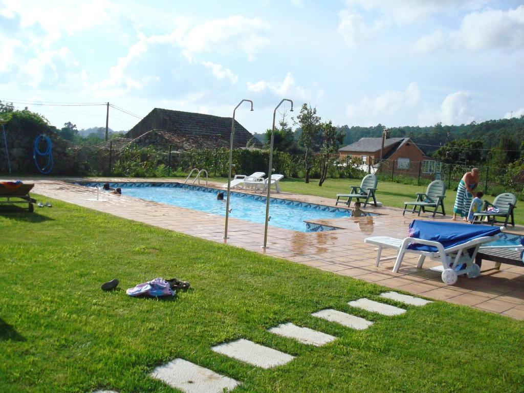 una piscina en un patio con gente sentada a su alrededor en Pazo Da Escola, en A Moreira