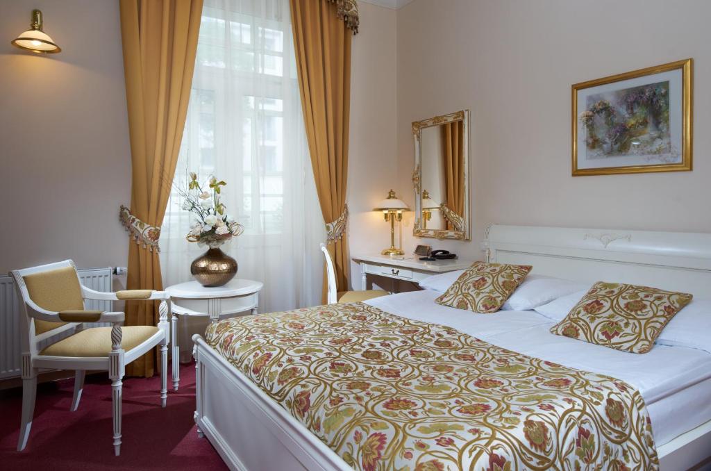 a hotel room with a bed and a desk and a window at Alqush Downtown Hotel in Prague