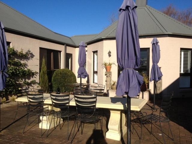 a group of tables and chairs with purple umbrellas at Greengate Bed and Breakfast in Robertson