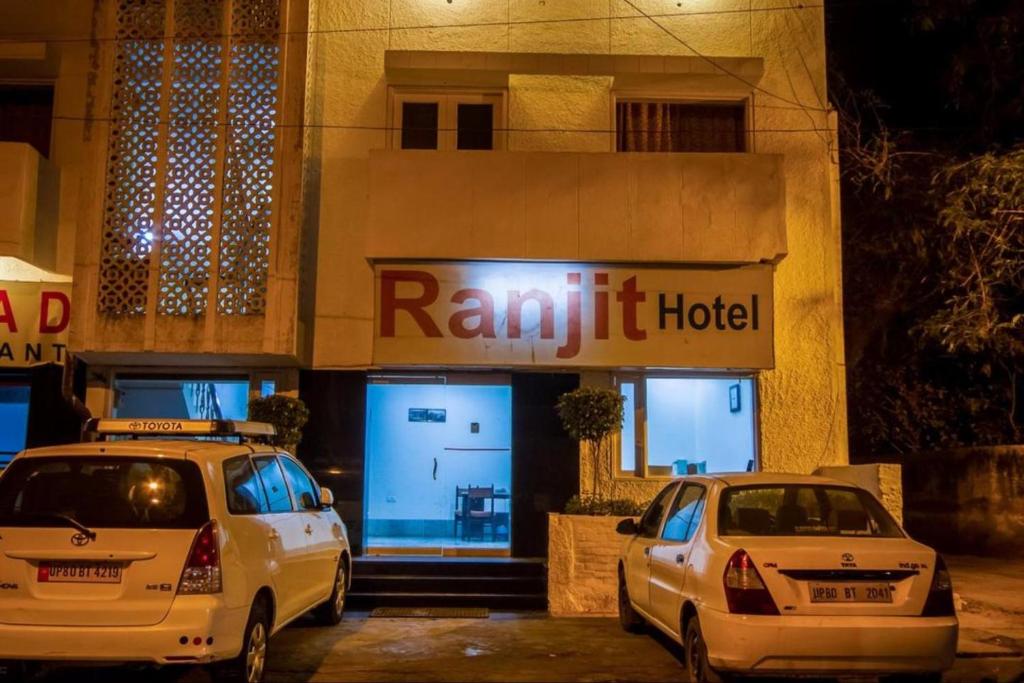 dos coches estacionados frente a un hotel por la noche en Hotel Ranjeet en Agra