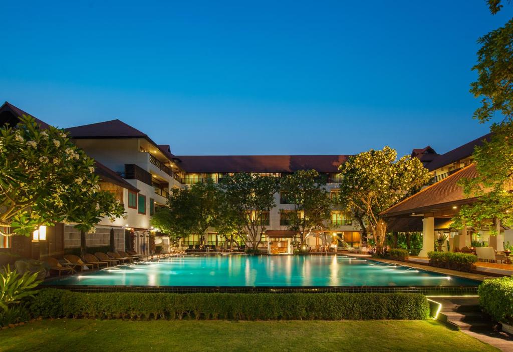 una foto di una piscina in un resort di notte di RatiLanna Riverside Spa Resort a Chiang Mai