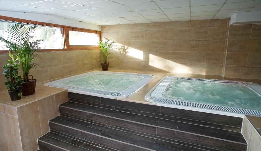 a jacuzzi tub in a room with two plants at Hôtel Club mmv Le Flaine *** in Flaine