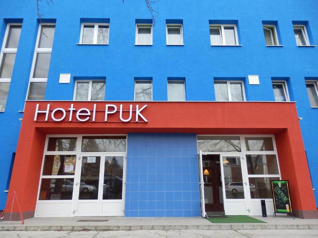 un segno di puk di un hotel di fronte a un edificio blu di Hotel Puk a Topoľčany