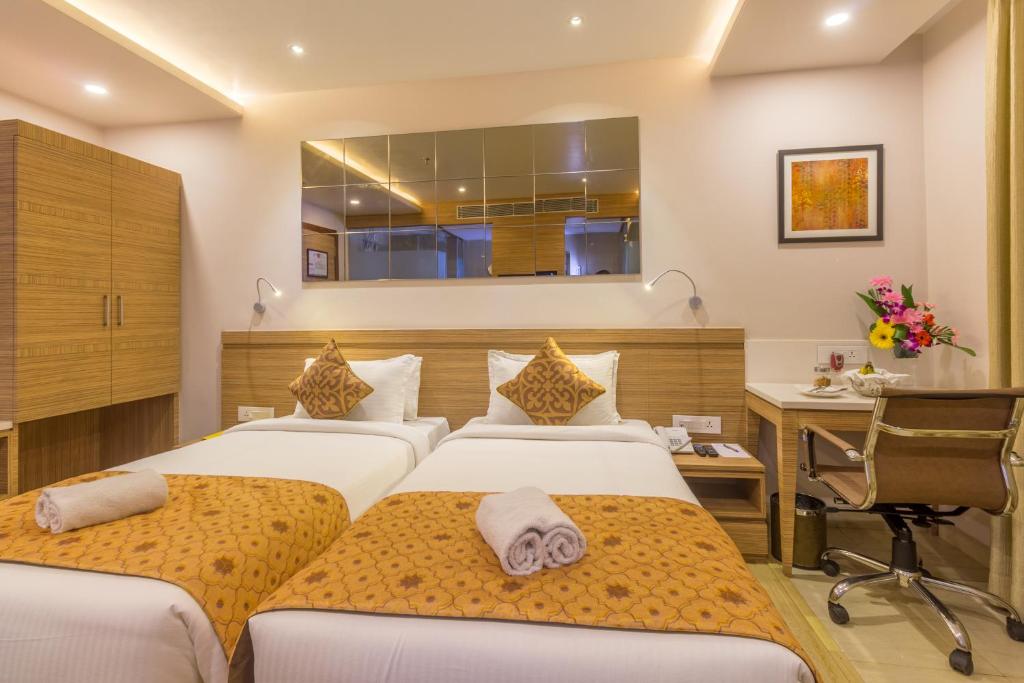 Habitación de hotel con 2 camas y escritorio en Hotel Palacio, en Guwahati