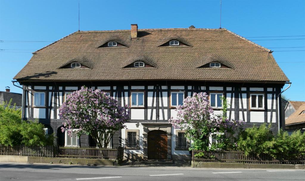 una casa antigua con techo de baldosa y flores en Goldberghaus Mauve, en Großschönau