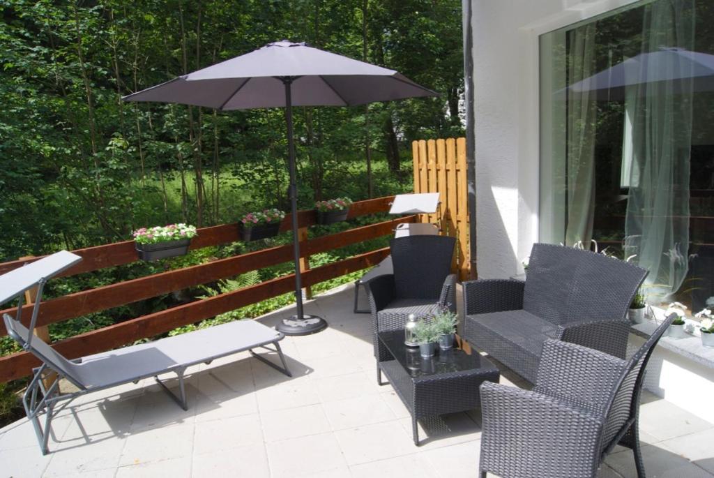 eine Terrasse mit einem Tisch, Stühlen und einem Sonnenschirm in der Unterkunft Ferienwohnungen TalBach in Simmerath