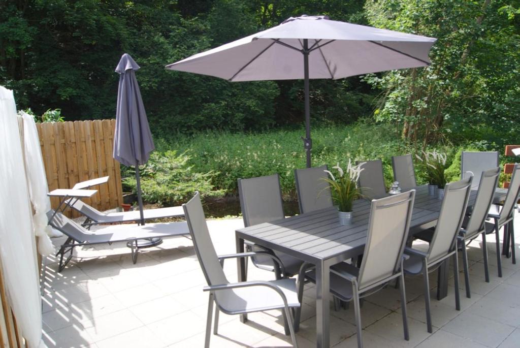 a wooden table and chairs with an umbrella and a patio at Ferienwohnungen TalBach in Simmerath