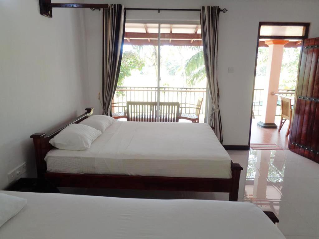 two beds in a hotel room with a balcony at Man Guest Polonnaruwa in Polonnaruwa