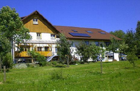 ein großes Haus auf einem Rasen mit Bäumen in der Unterkunft Landhaus Breg in Hergensweiler