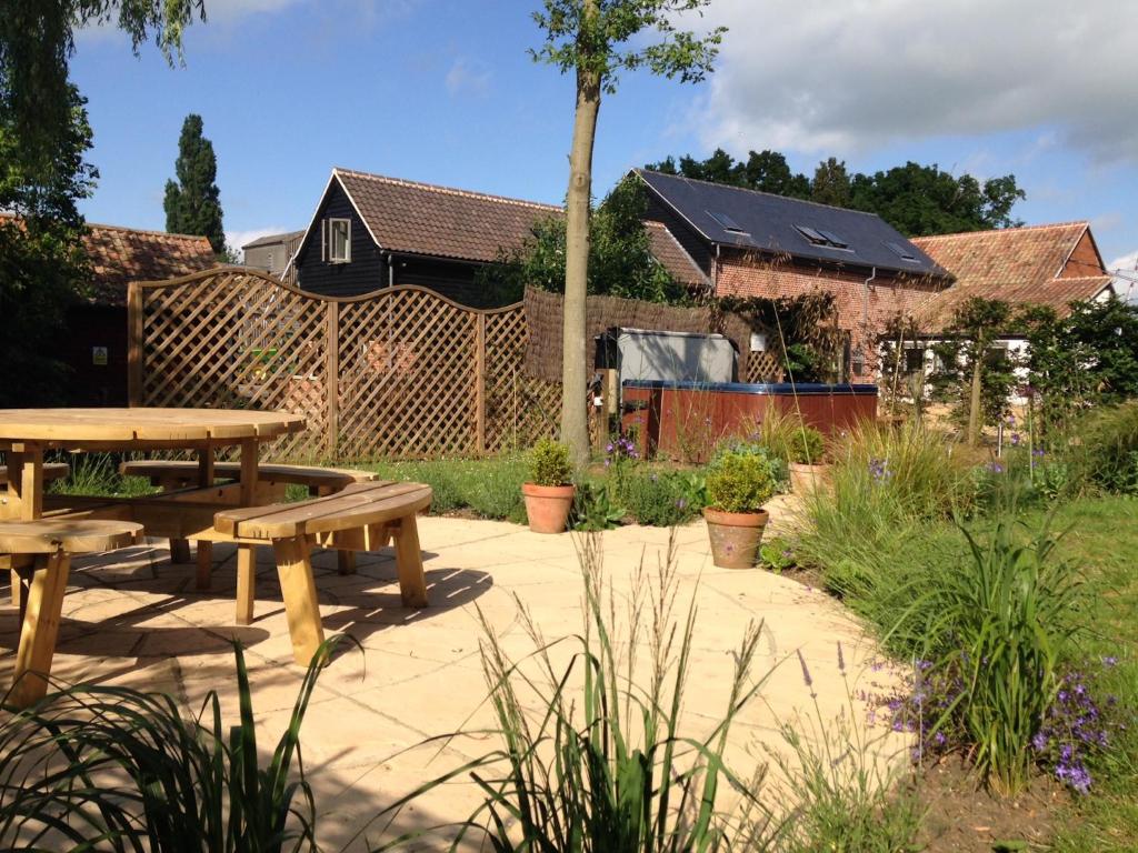 a patio with a wooden picnic table in a garden at Fullers Hill Cottages in Little Grandsen