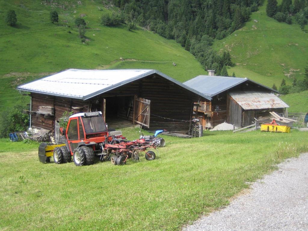 ciągnik zaparkowany na polu obok budynku w obiekcie Pension Hedegghof w mieście Grossarl