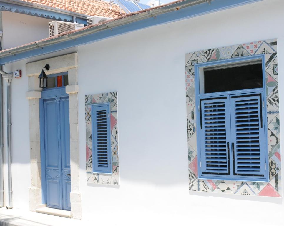 un edificio blanco con persianas azules y una ventana en The Stable, en Limassol