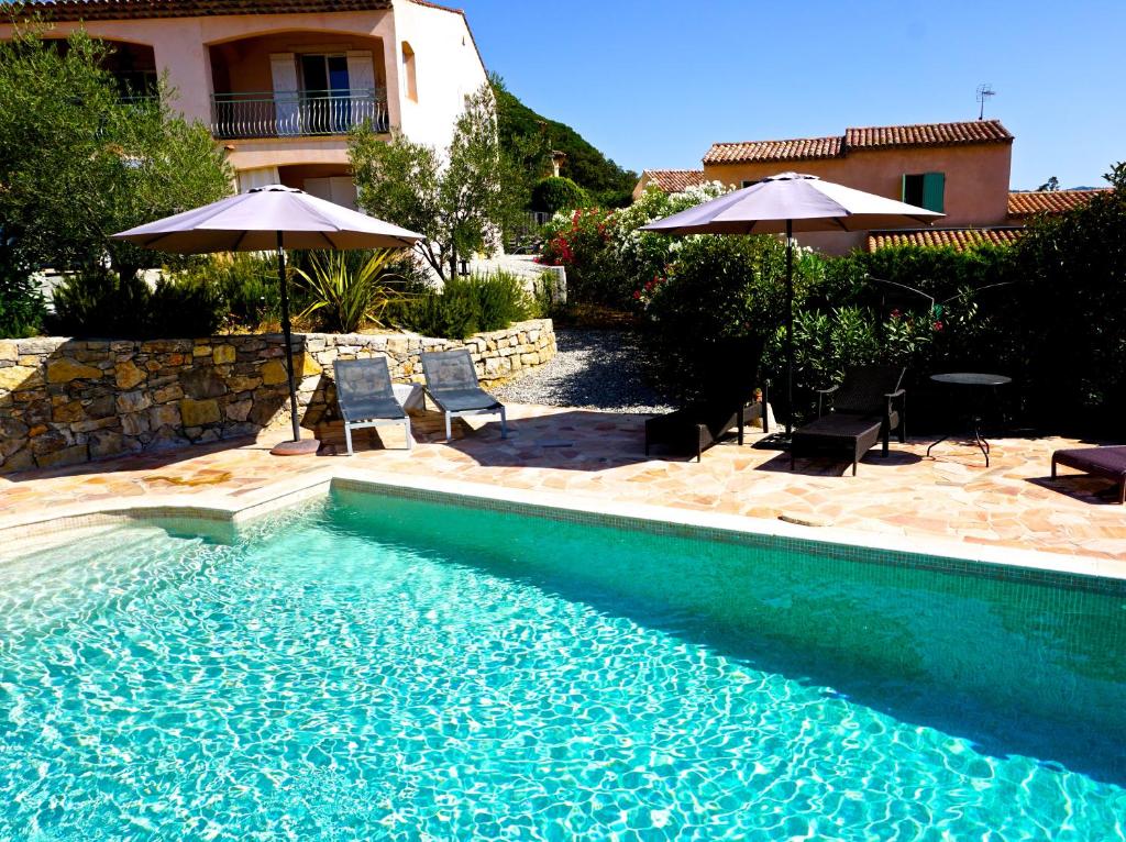 a swimming pool with chairs and umbrellas next to a house at Lone Star House in Sainte-Maxime