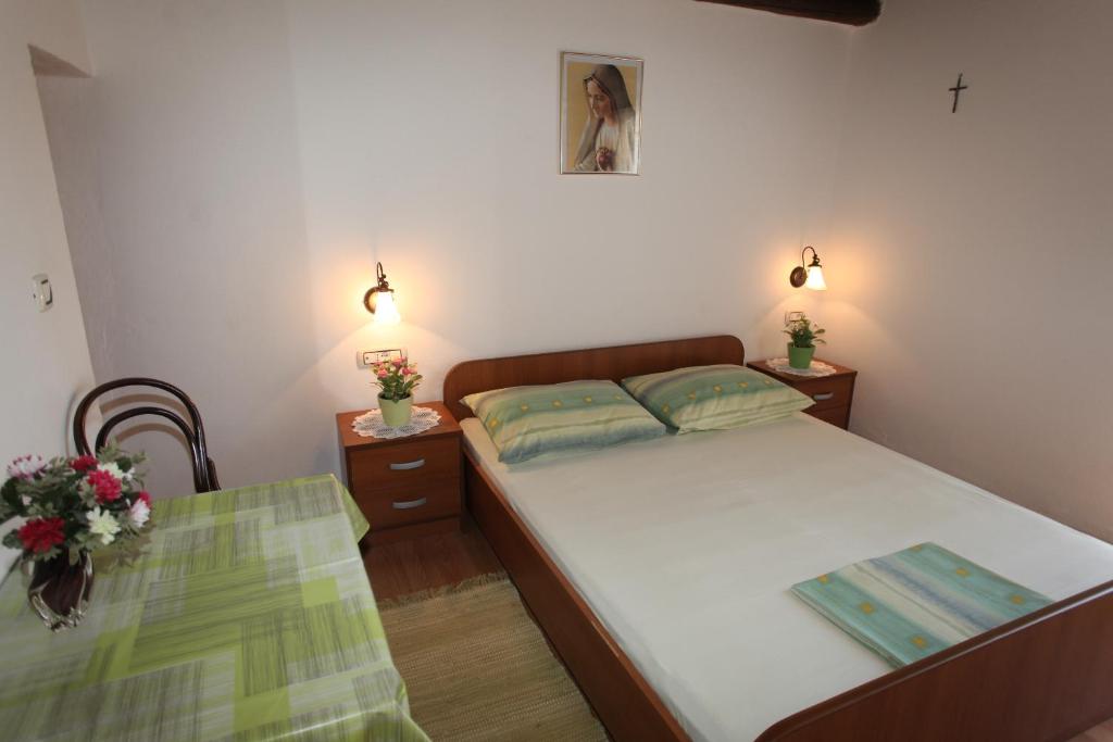 um pequeno quarto com uma cama e uma mesa em Accommodation Lily em Vrana