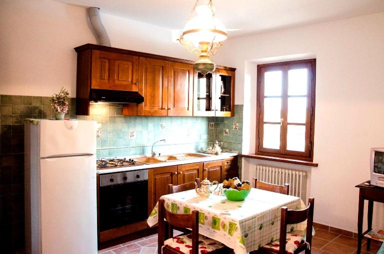kuchnia ze stołem i białą lodówką w obiekcie Agriturismo Podere dei kiwi w mieście Chiesina Uzzanese