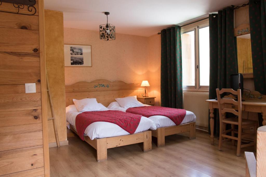 Villar-dʼArène的住宿－古幣酒店，一间卧室设有两张床、一张桌子和一个窗口