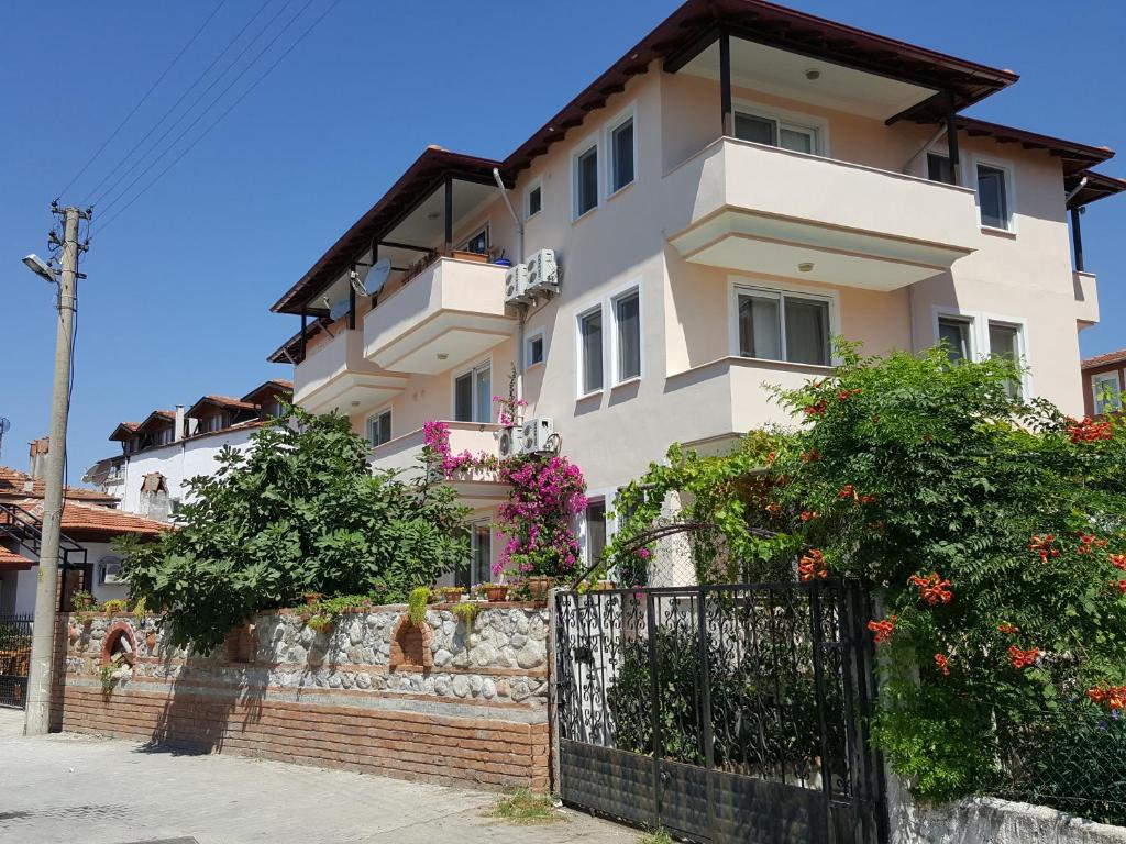 a white house with a fence in front of it at Karya Apartments in Koycegiz