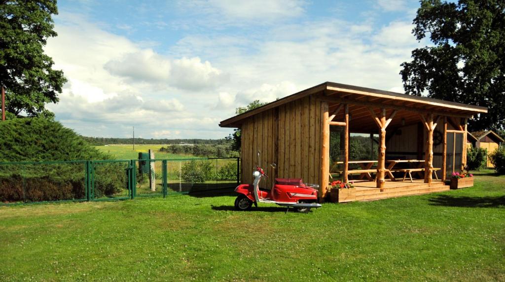 un piccolo capanno con uno scooter rosso parcheggiato nell'erba di Treimani Country House a Treimani