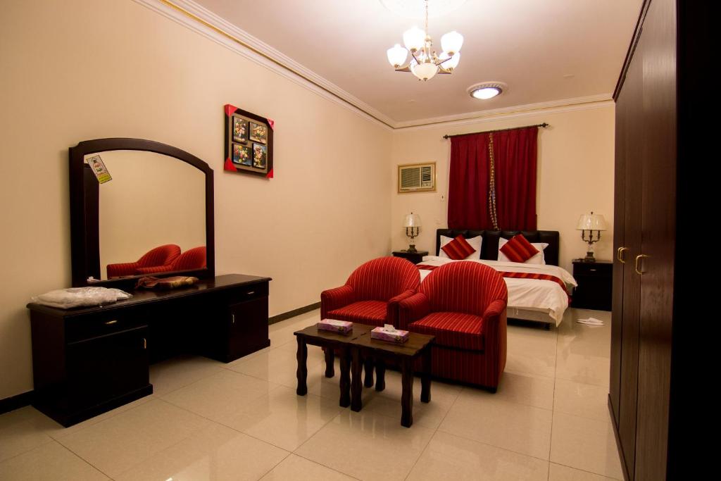 a bedroom with a bed and a red chair and a mirror at Shaza Al Khamis شذا الخميس in Khamis Mushayt