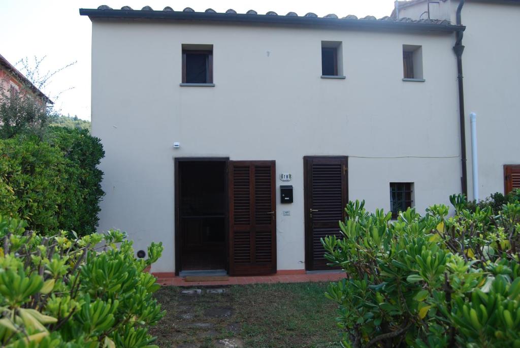 a white building with brown doors and some bushes at Ca' Faggiolo in Lamporecchio