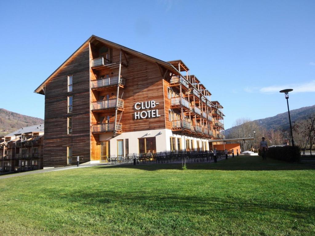 a large wooden hotel with a grass field in front of it at Club Hotel am Kreischberg in Sankt Georgen ob Murau