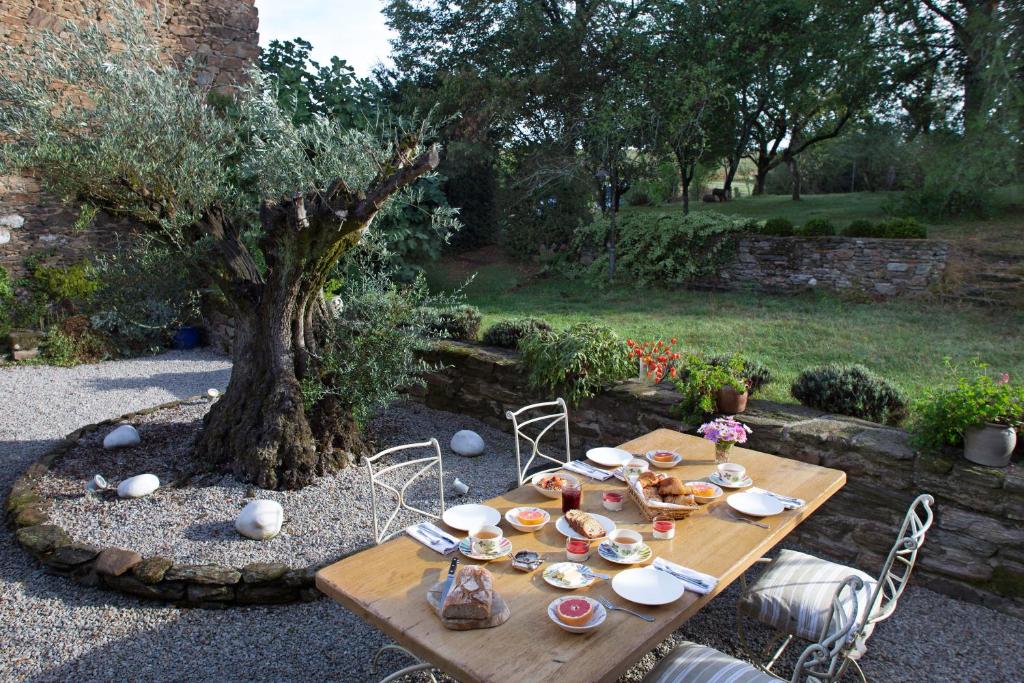 uma mesa de madeira com pratos ao lado de uma árvore em La Maison de la Souque em Mirandol-Bourgnounac