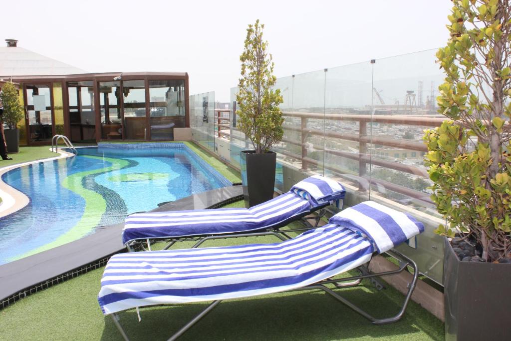 2 tumbonas y una piscina en un edificio en Sea View Hotel Dubai, en Dubái