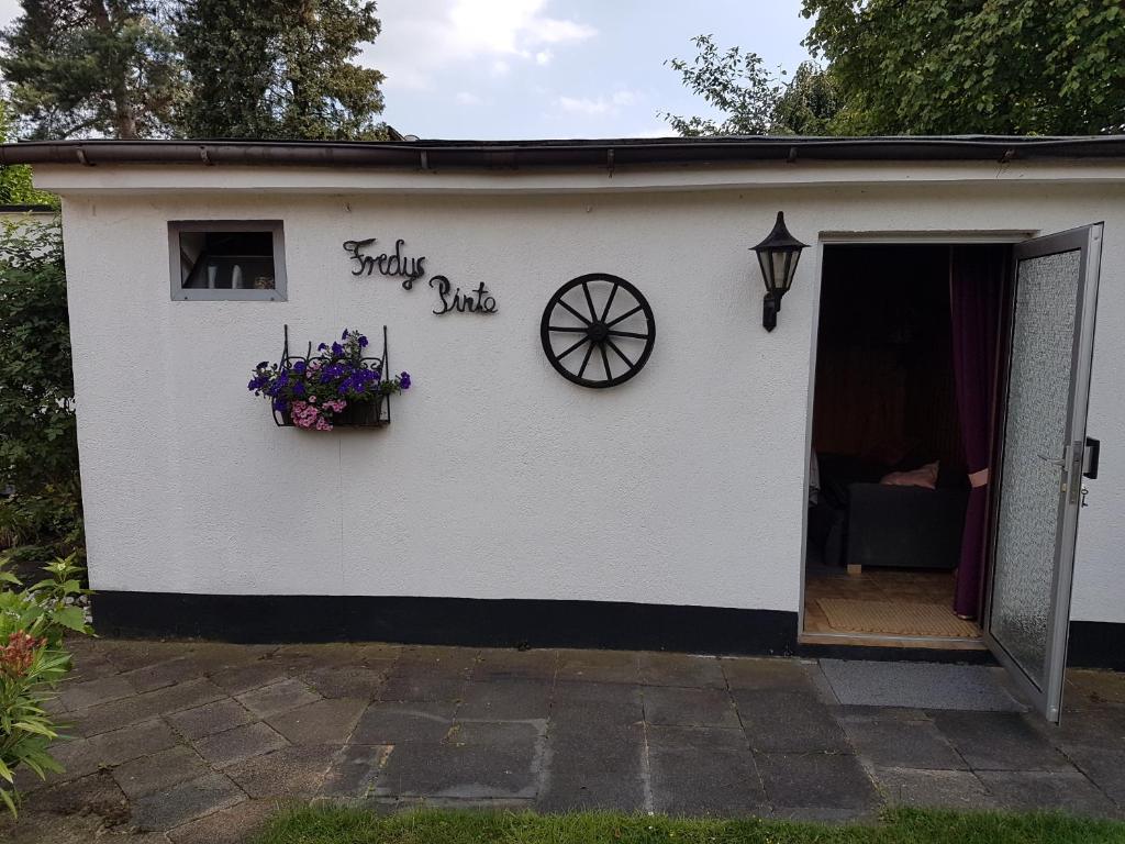 um pequeno galpão branco com uma porta e flores nele em Opdenberg em Dusseldorf