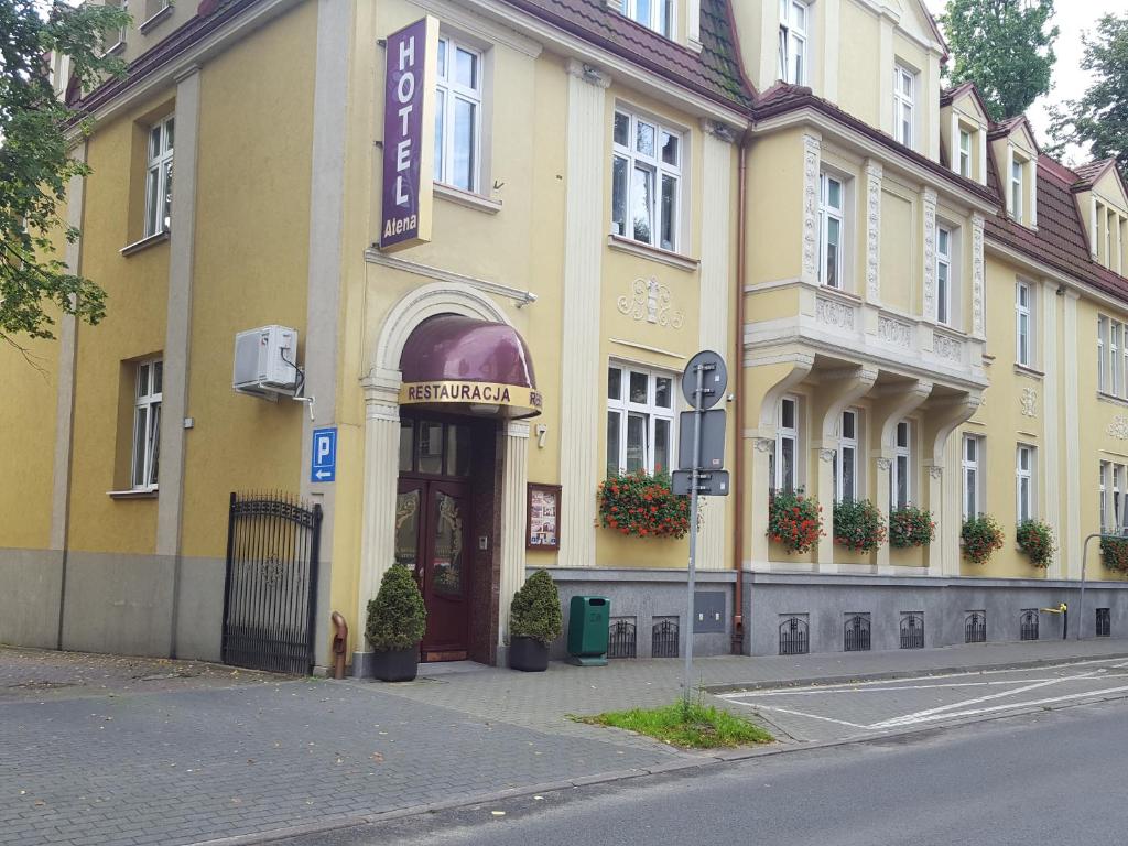 ein gelbes Gebäude mit einem Schild auf der Vorderseite in der Unterkunft Hotel Atena in Słupsk