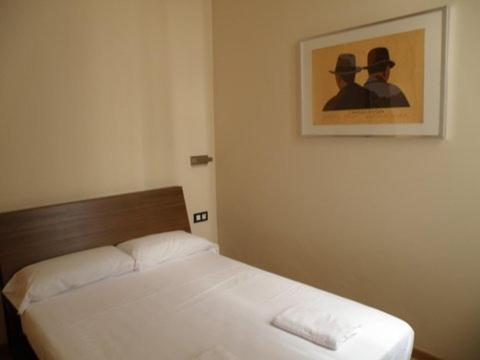 a bed in a bedroom with a picture on the wall at Center Gran Via in Barcelona