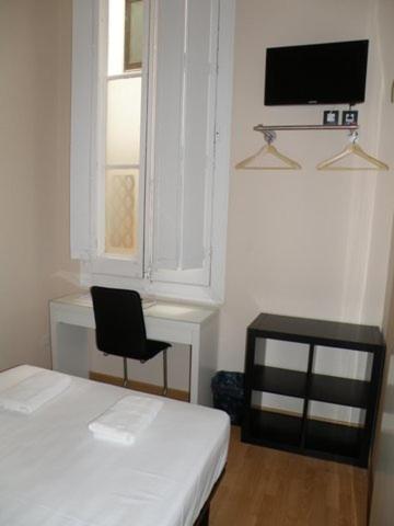 a room with a bed and a chair and a television at Center Gran Via in Barcelona