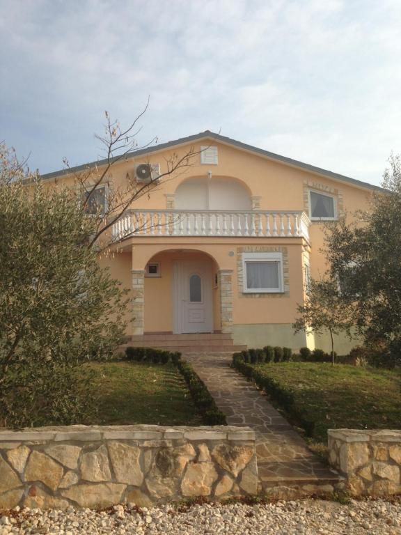 a yellow house with a stone walkway in front of it at Apartments Brkanac in Umag
