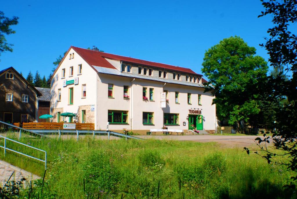 ein großes weißes Gebäude mit rotem Dach in der Unterkunft Waldgasthaus & Pension Teichhaus in Holzhau