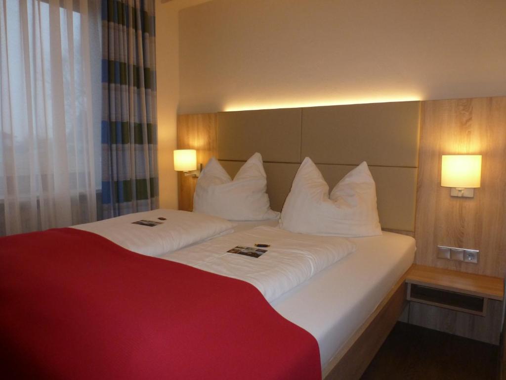 Cette chambre comprend un grand lit avec des oreillers blancs. dans l'établissement Hotel das Möwenstübchen, à Wremen