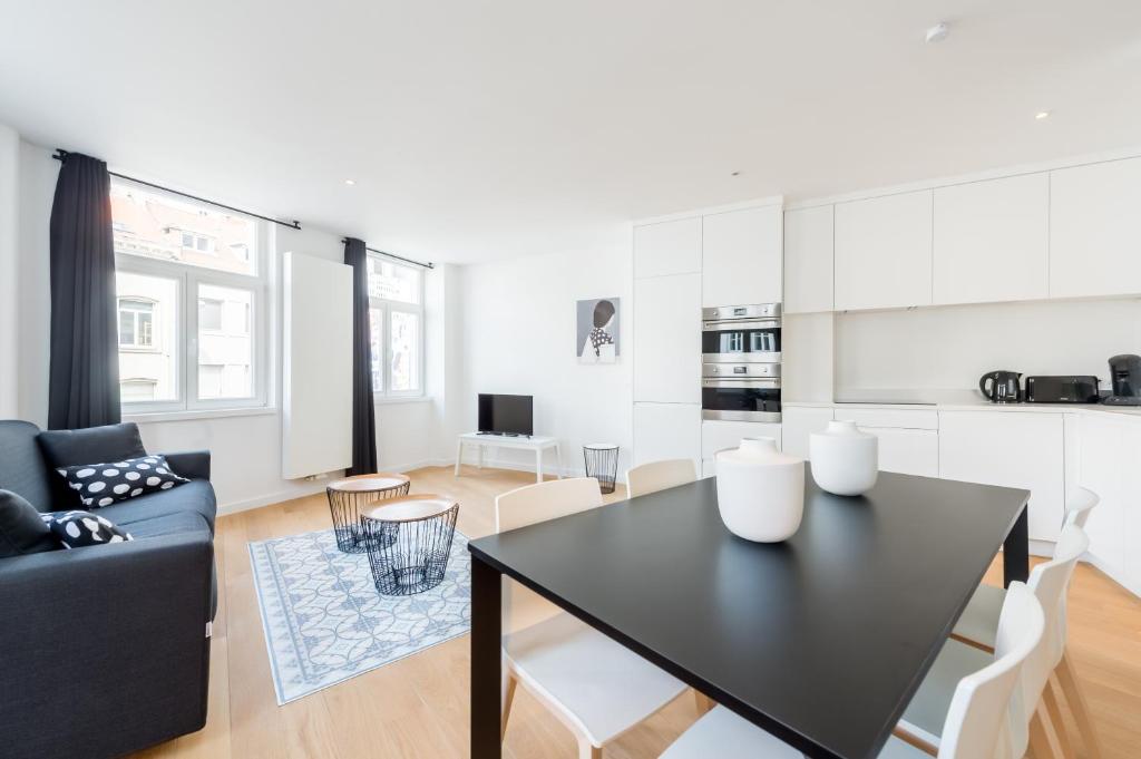 uma cozinha e sala de estar com uma mesa preta e cadeiras em Smartflats - Toison d'Or em Bruxelas