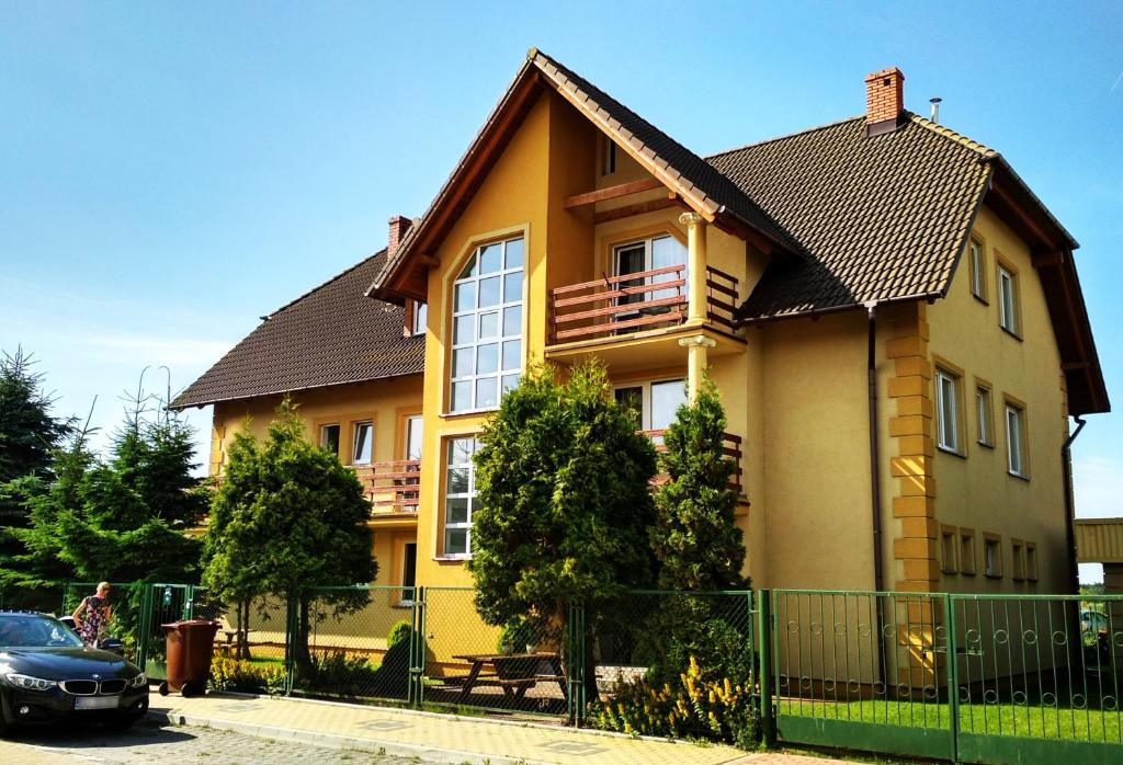 une maison jaune avec une clôture devant elle dans l'établissement Słoneczne Uroczysko, à Międzywodzie