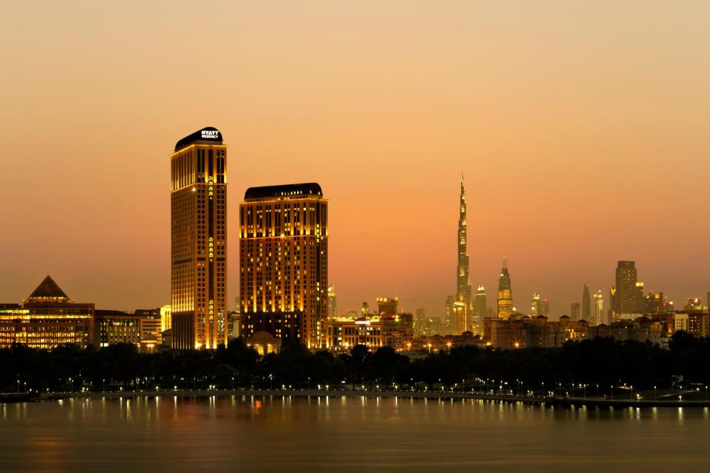 a city at night with tall buildings and a clock tower at Hyatt Regency Creek Heights Residences in Dubai