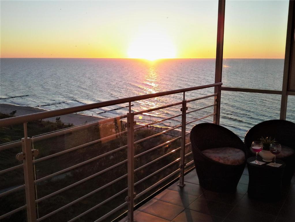 a balcony with a view of the ocean at sunset at Apartamenty Porta Mare in Dziwnówek