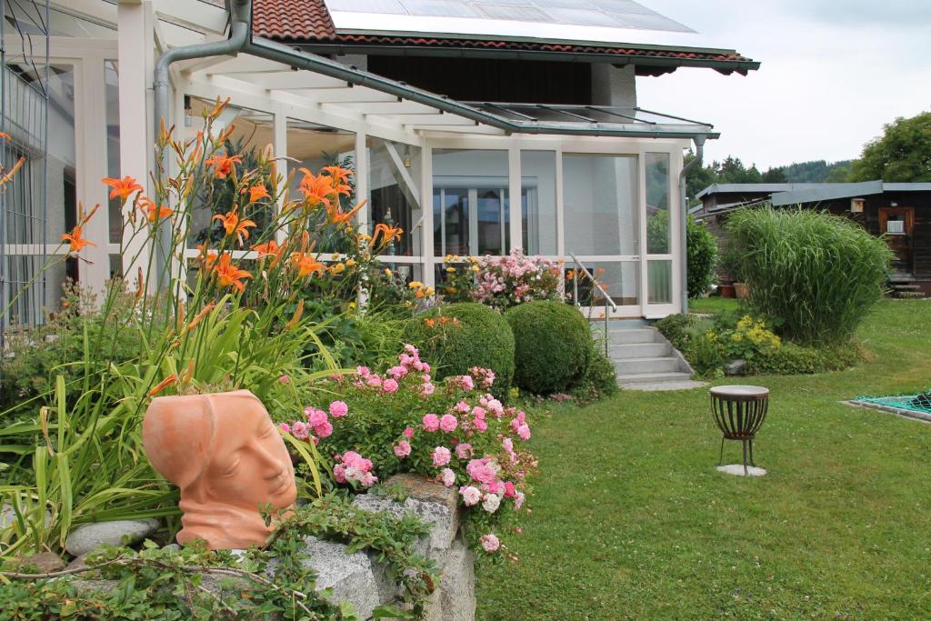 a house with a garden with flowers in the yard at Ferienwohnung am Altenstein in Grafenau