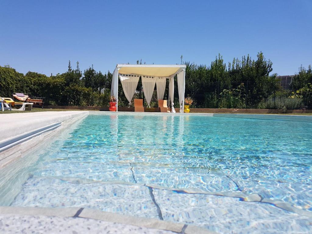 einen Pool mit einem Pavillon im Hintergrund in der Unterkunft Casa Vacanze Il Giardino Dei Girasoli in Marina di Ragusa