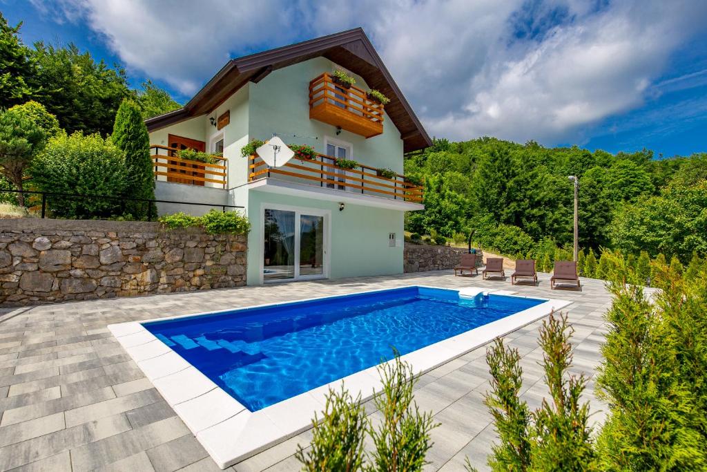 a villa with a swimming pool in front of a house at Villa Dino Tin in Krasno Polje