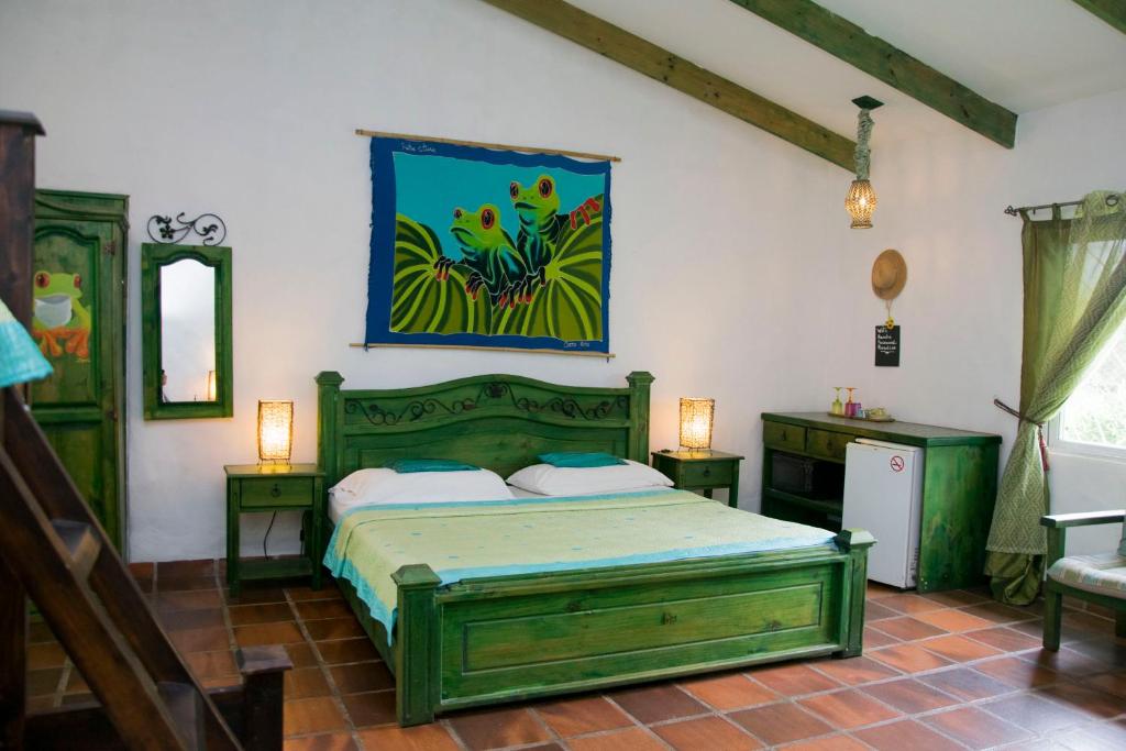 a bedroom with a green bed and a painting on the wall at Villa Margarita in Alajuela City