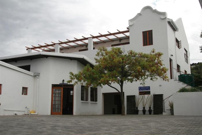 a white building with a tree in front of it at Queen Manor Boutique Guest House in Graaff-Reinet
