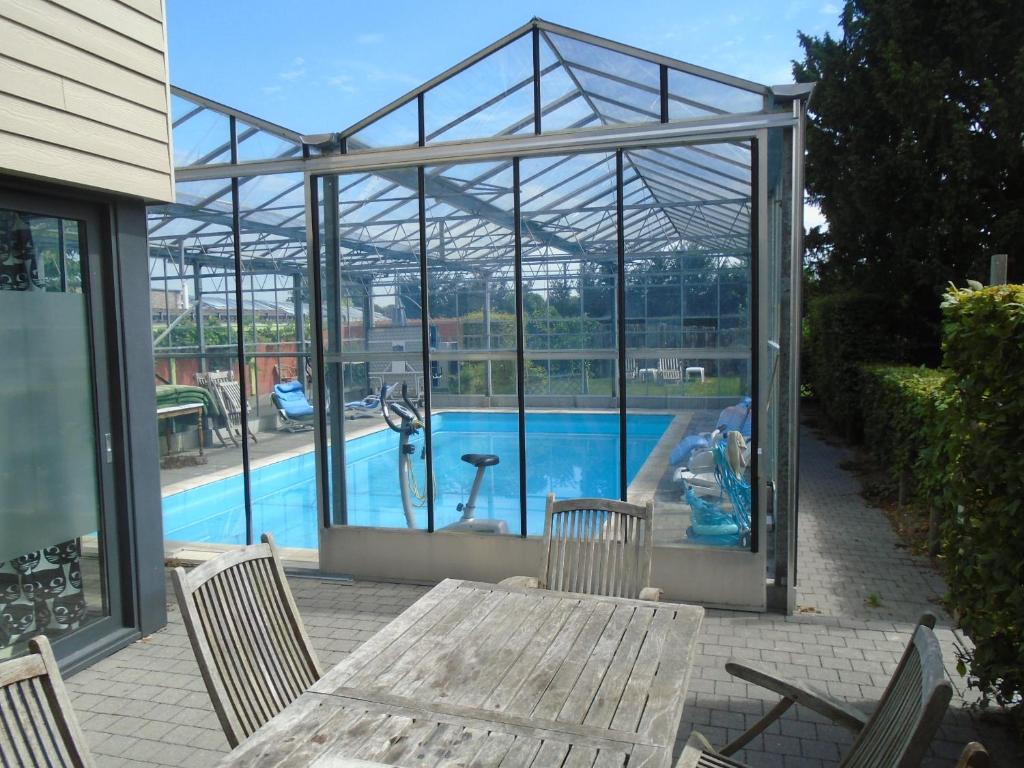 ein Glashaus mit einem Tisch und Stühlen sowie einem Pool in der Unterkunft Apartment Meylhof in Kontich