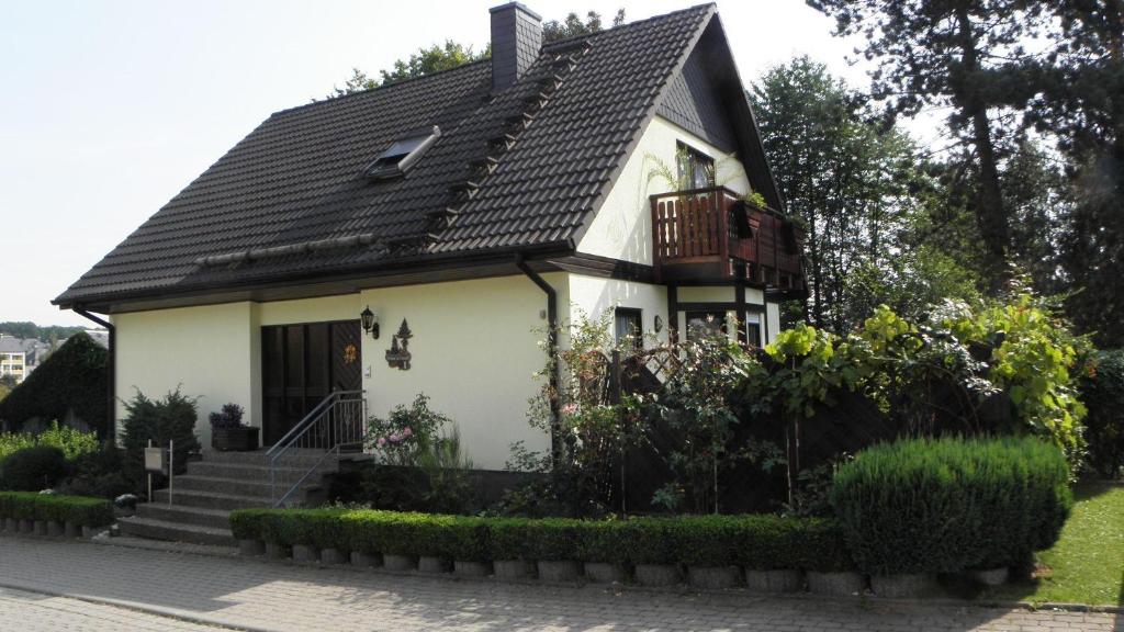 a small white house with a balcony and stairs at FeWo-Schmidt-im-Erzgebirge in Gelenau