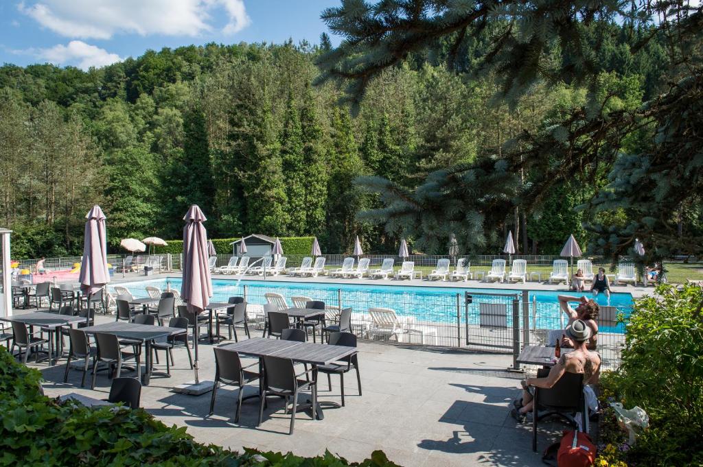 a pool with tables and chairs and umbrellas at Domaine Long Pre in Stavelot