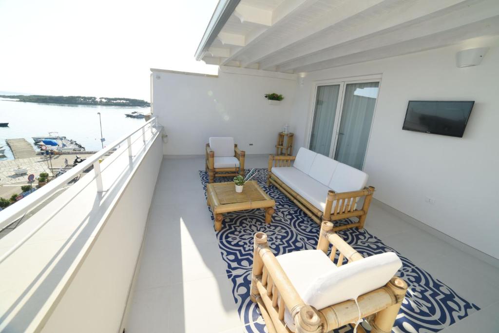 einen Balkon mit Stühlen, einem Sofa und einem Tisch in der Unterkunft Latino Rent Room B&B vista mare in Porto Cesareo