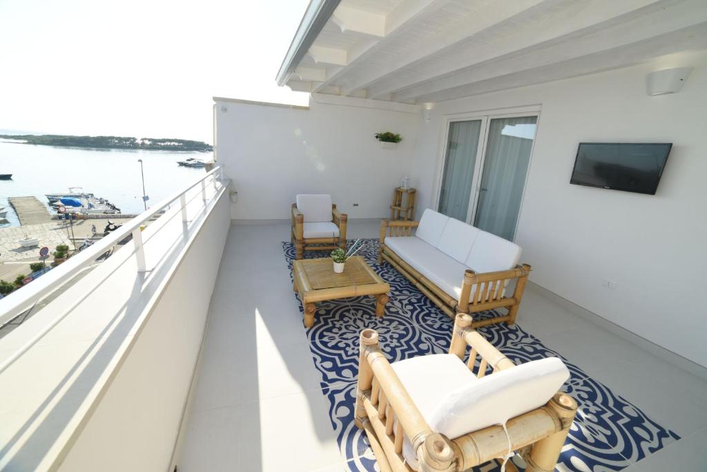 a balcony with chairs and a couch and a table at Latino Rent Room B&B vista mare in Porto Cesareo